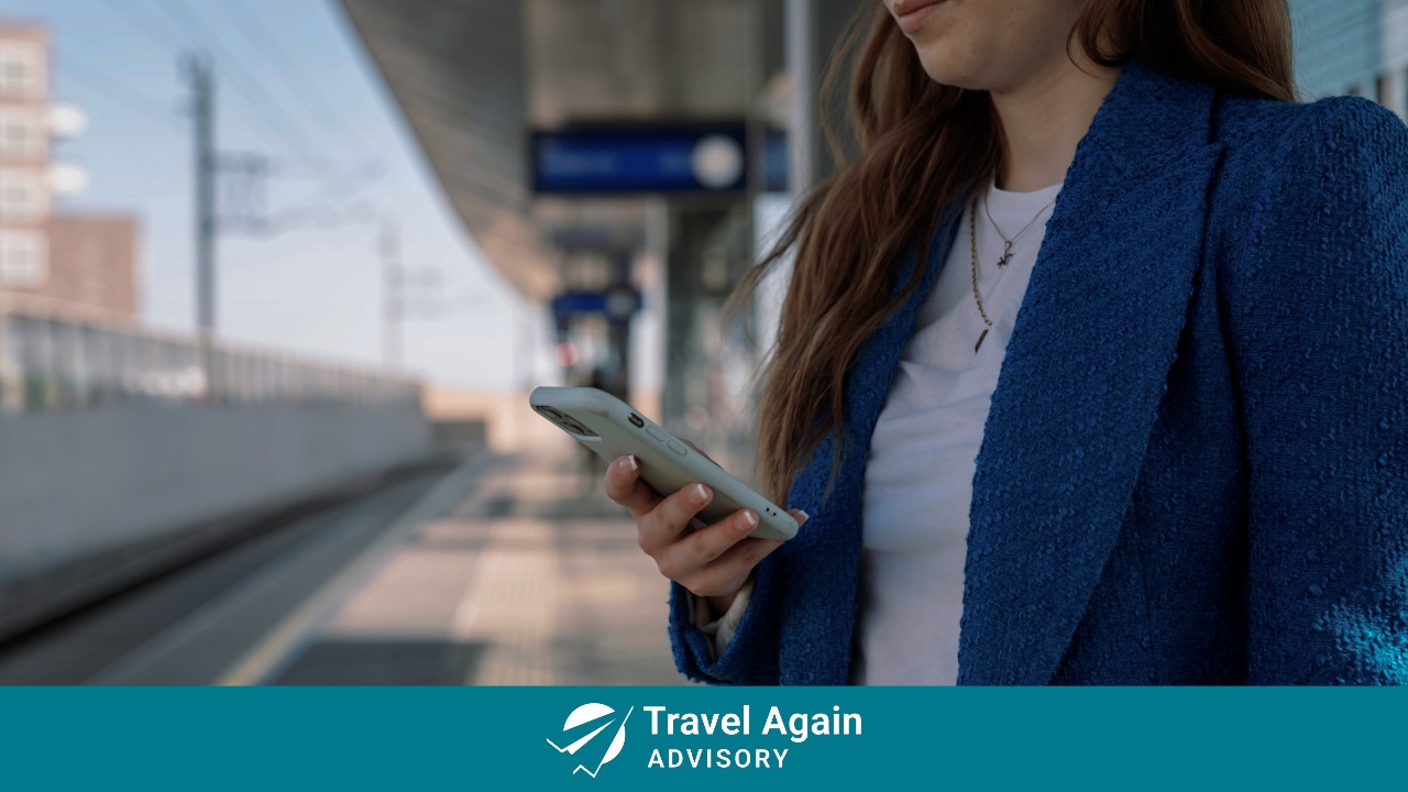 A woman looking at Navan's travel tech on her phone while waiting at a train station